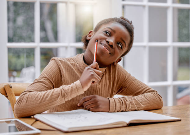 shot of a little girl doing homework at home - child thinking writing little girls imagens e fotografias de stock