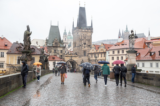 Prague - March 11, 2020: Rainy day in Prague. Tourists visit Charles Bridge in any weather