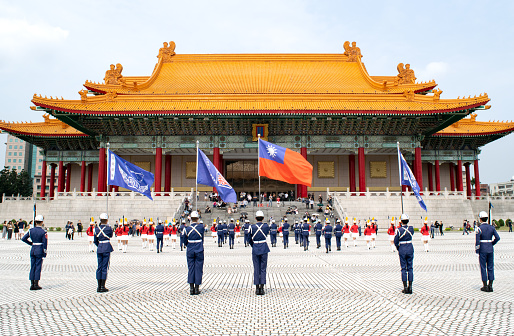Young members of a military-style marching troupe hold flags and perform in blue uniforms outside of the Taipei Performing Arts Center (Style of Traditional Taiwanese Temple) in Taipei, Taiwan