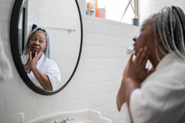 Senior woman applying facial moisture on face at home