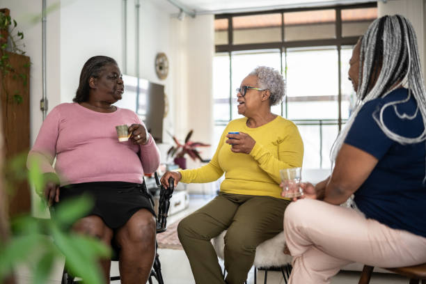 Senior friendswomen talking and drinking coffee or tea at home