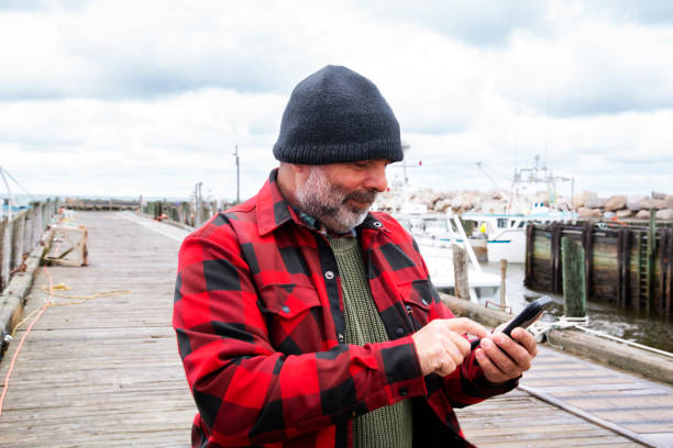 istock A fisherman on a wharf using his mobile phone. 1356377350