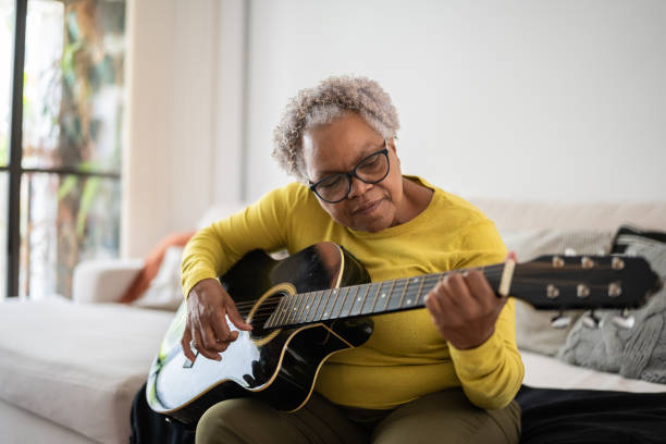 istock Senior woman playing guitar at home 1356377409