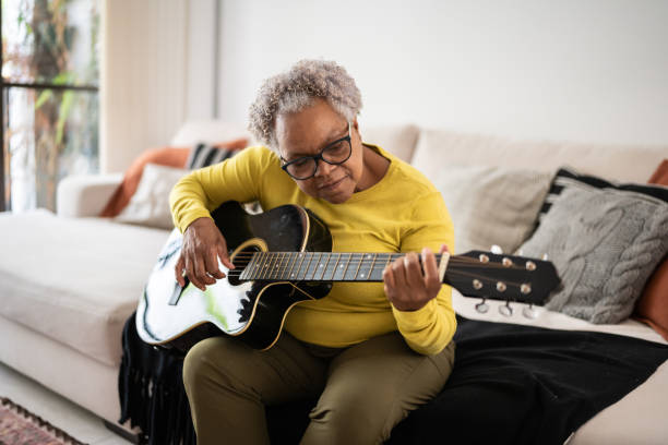 istock Senior woman playing guitar at home 1356377432