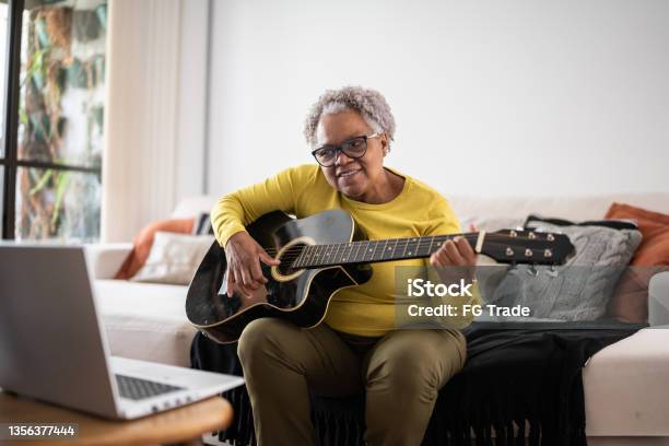 Senior Woman Learning To Play Guitar At An Online Class At Home Stock Photo - Download Image Now