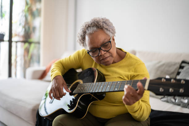 Senior woman playing guitar at home