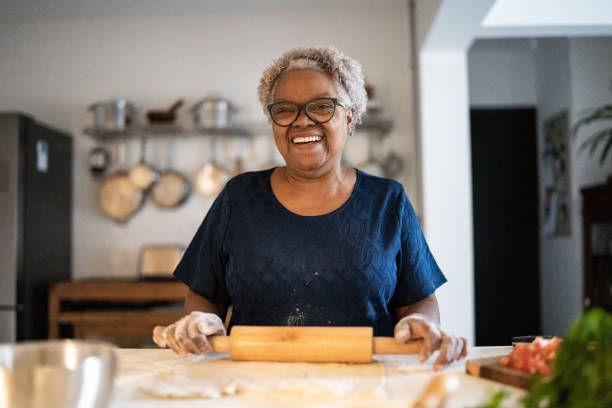 portrait d’une femme âgée cuisinant à la maison - home baking photos et images de collection