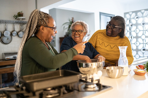 Senior woman filming sisters or friends baking/cooking at home