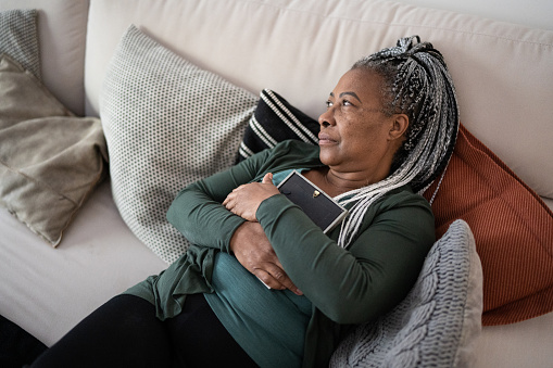 Senior woman holding a picture frame missing someone at home