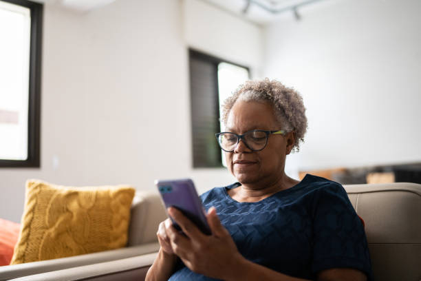 Senior woman using a mobile phone at home Senior woman using a mobile phone at home reading glasses stock pictures, royalty-free photos & images