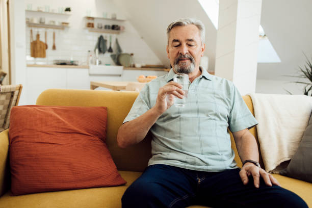 istock Senior man sitting on the sofa and refreshing with water 1356379006