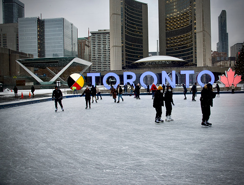 Toronto, Ontario, Canada- November 29, 2021: People skating at the ice rink, which is located at Toronto city hall’s Nathan Phillips Square.
