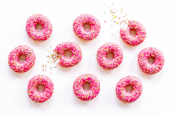 istock Pink frosted donuts with colorful sprinkles. Bakery background 1356380433
