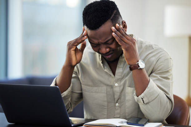 istock Shot of a young businessman suffering from a headache while working from home 1356380612