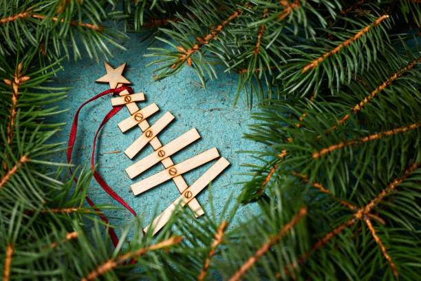 new year composition from wooden christmas tree on a blue paper background surrounded by fir branches - new years eve christmas paper christmas fir tree imagens e fotografias de stock