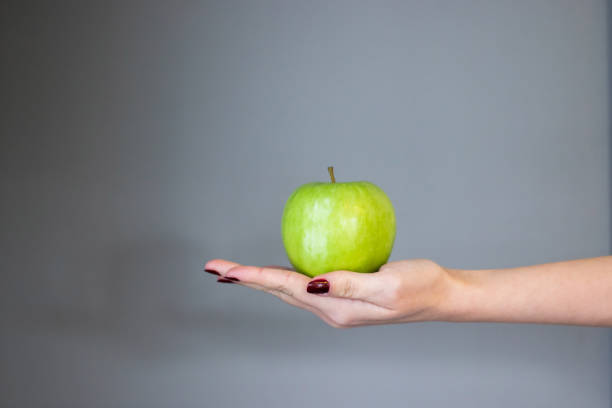 istock green apple standing in woman's hand, on isolated background 1356381710