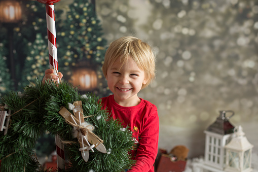 Cute blond toddler child, playing with snow and christmas decoration, studio shot