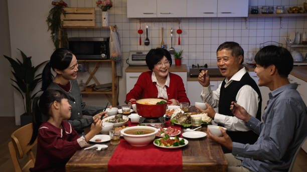 istock cheerful asian family members having fun chatting and laughing at dining table while enjoying big meal on chinese new year’s eve dinner party at home 1356385334