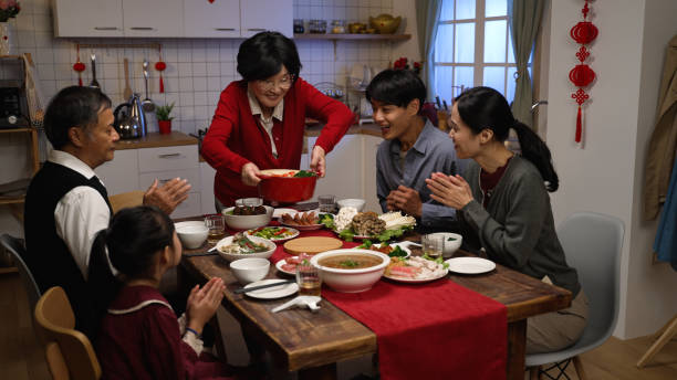 веселая азиатская покойница бабушка в красной одежде, поднимая большой палец вверх во время подачи своей специальности на стол, испытывая � - asian meal стоковые фото и изображения