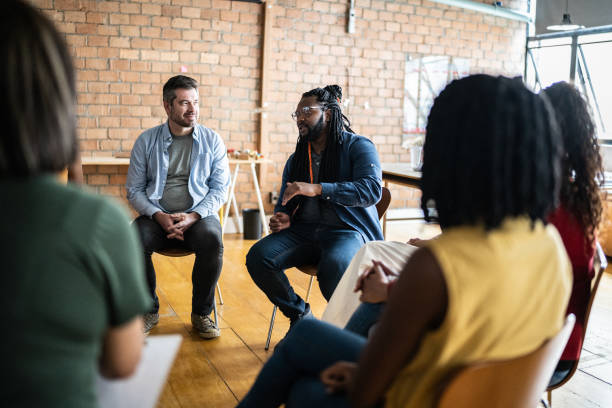 istock Mid adult man talking in a meeting or group therapy 1356385630