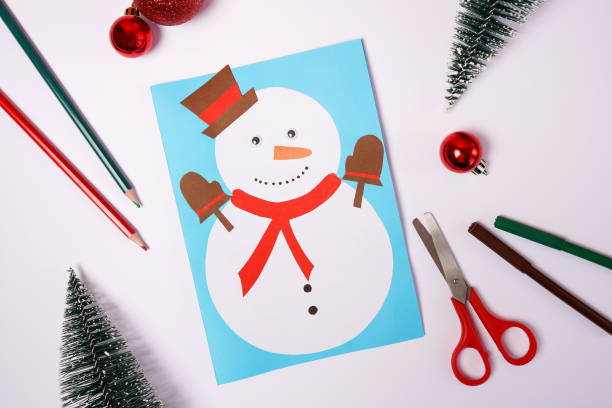 istock DIY Christmas card with snowman from colored paper on white background 1356385706