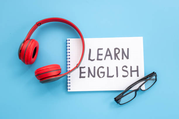 istock English lessons concept. Headpones with notebook on student table desk 1356385756
