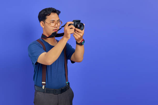 istock Handsome photographer taking photo on purple background 1356385813