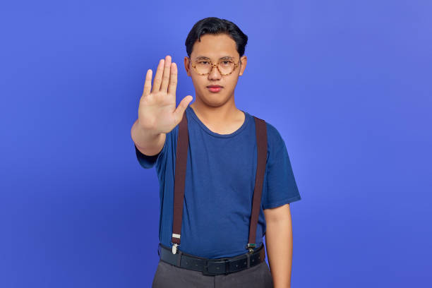 istock Asian young man doing stop gesture with palm isolated over purple background 1356386092