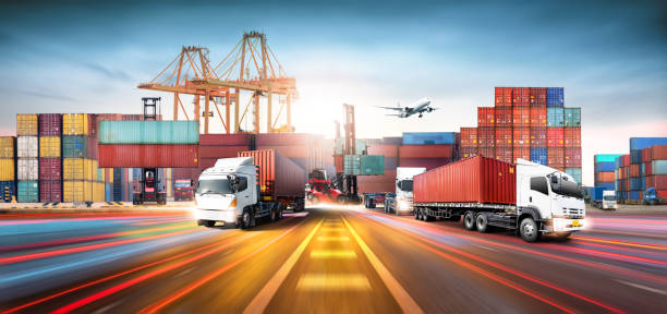 Global business logistics import export and container cargo freight ship during loading at industrial port by crane, container handlers, cargo plane, truck on highway, transportation industry concept stock photo