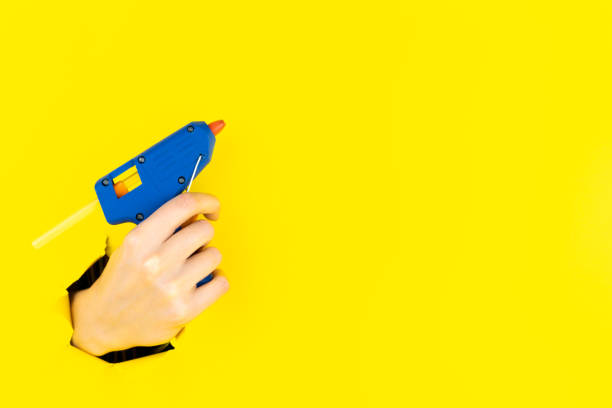 istock Hand is holding hot pistol glue gun in torn hole 1356388009