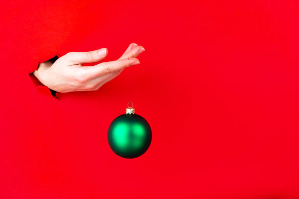 istock Hand is holding christmas tree sparkling toy in torn hole 1356388059