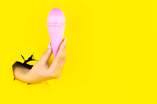 istock Hand is holding pink egg in colorful ice cream cone 1356390384