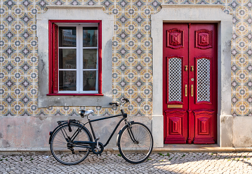 black vintage bicycle parked on the facade of a traditional Portuguese tiled house.
