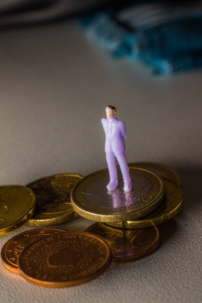 istock Human figurine standing on coins 1356397511