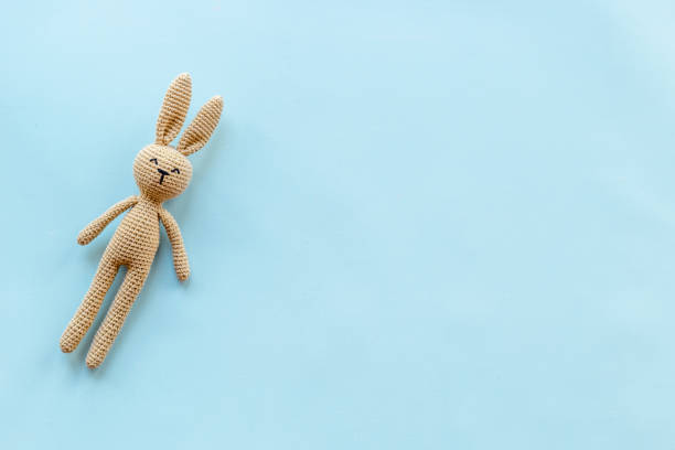 Knitted baby toy rabbit for newborn - background for baby shower stock photo