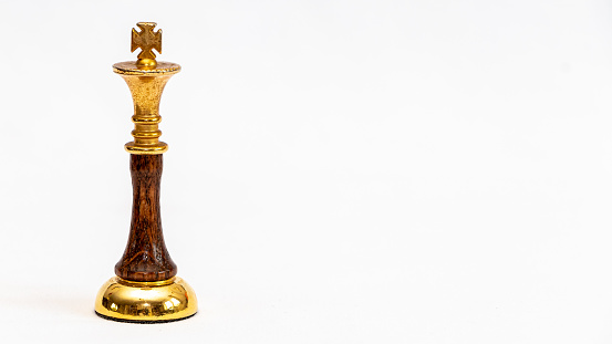 A golden King chess piece on a white background