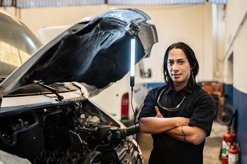 Portrait of Non-Binary person repairing a car in auto repair shop