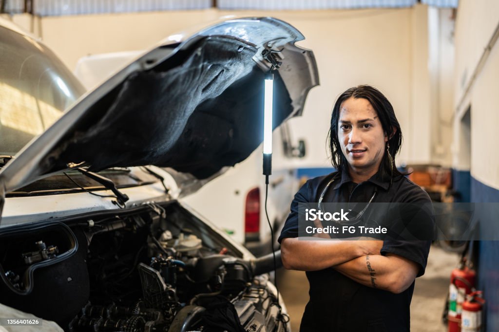 Portrait of Non-Binary person repairing a car in auto repair shop Non-Binary Gender Stock Photo