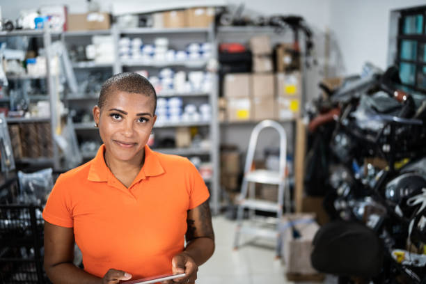 portrait of a woman taking inventory with a digital tablet in a auto repair shop - sales clerk imagens e fotografias de stock