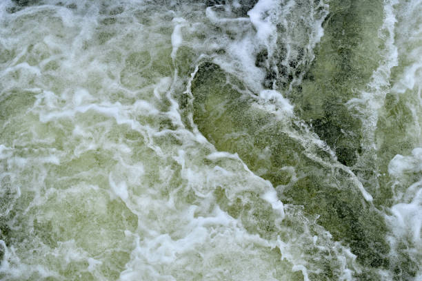 A textured pattern created by foaming water cascading down from a dam.