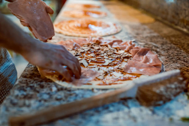 istock Closeup hand of chef baker making pizza at kitchen. The process of making pizza. Hands preparing a pizza. 1356402980