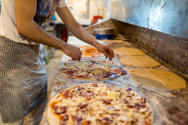 istock Closeup hand of chef baker making pizza at kitchen. The process of making pizza. Hands preparing a pizza. 1356402994