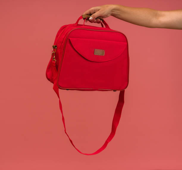 istock red travel bag in hand on pink background 1356404302