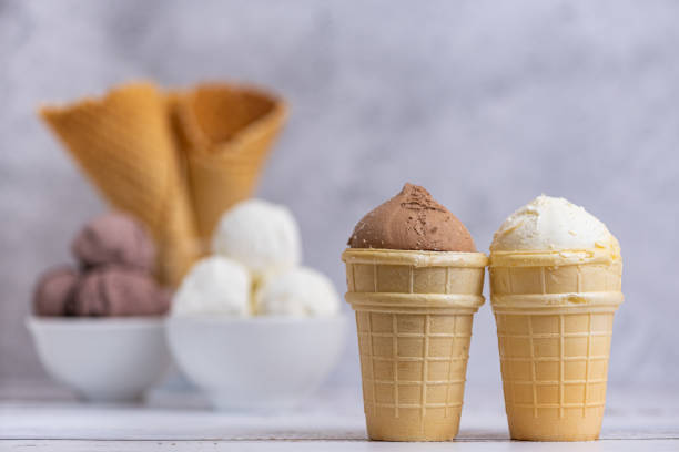 istock Bowl of vanilla and chocolate ice cream. and waffle cones on light background. Side view 1356405772