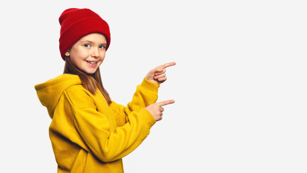 Hipster girl points with both forefinger on copy space for your advertising
