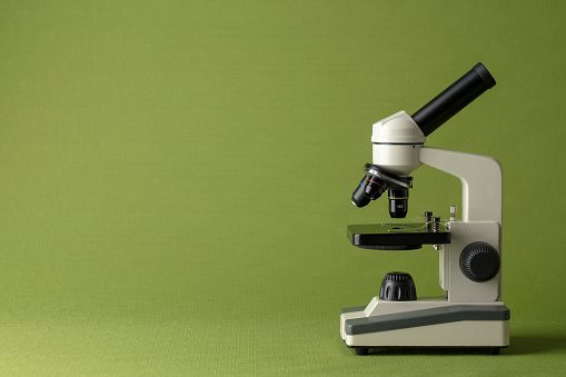 Microscope on a green background with space for copy.