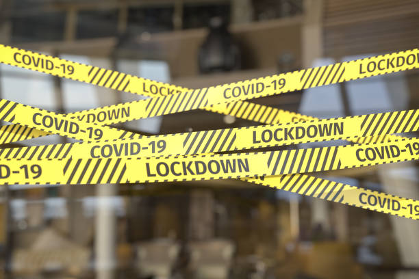 Barrier Tape restricting access to a restaurant or shop. Warning text "COVID-19" and "LOCKDONW" on the tape. stock photo