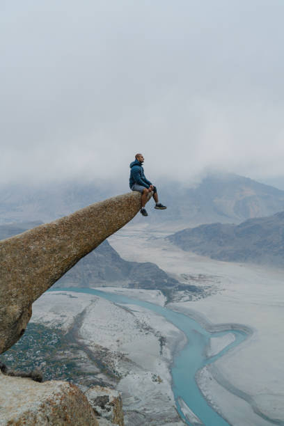 istock Man sitting on rock and looking at river in Himalayas 1356409600