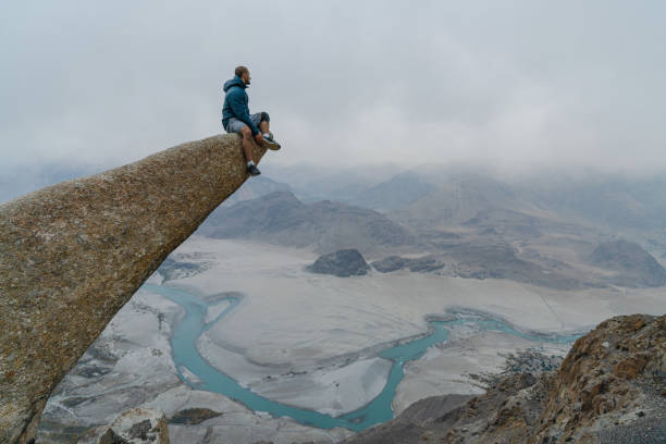 istock Man sitting on rock and looking at river in Himalayas 1356409605