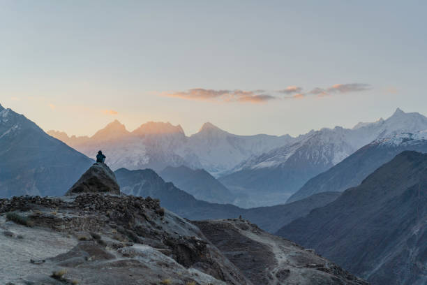 istock Man sitting on rock and looking at river in Himalayas 1356410257